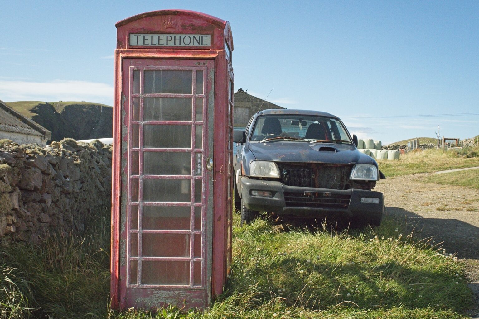 Observational documentary photography of a classic red telephone box and a rugged 4x4 vehicle in a remote Shetland landscape