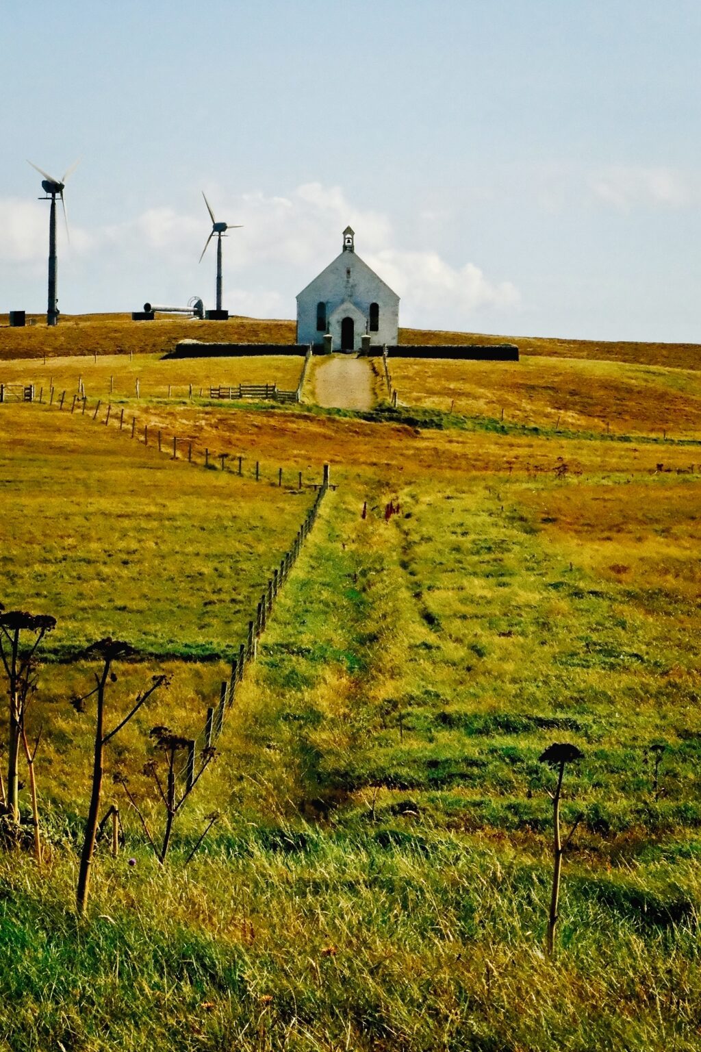 A minimalist perspective shot of a single-track road leading toward a lonely church building on the island's edge