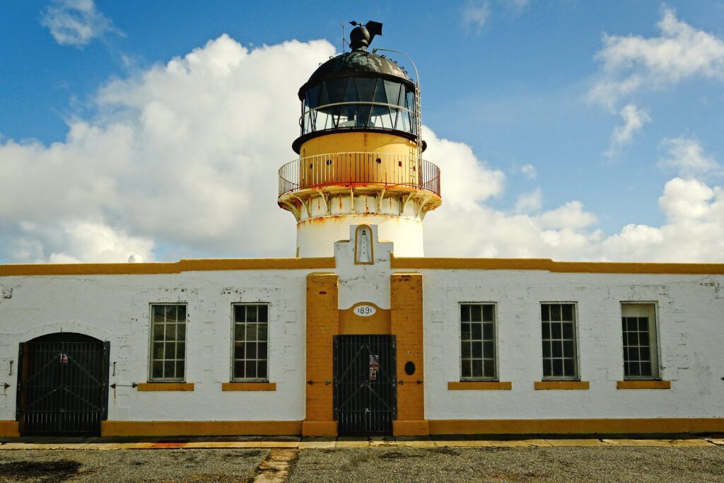 Symmetrical architectural editorial of a Fair Isle lighthouse entrance, showing the bold yellow and white masonry