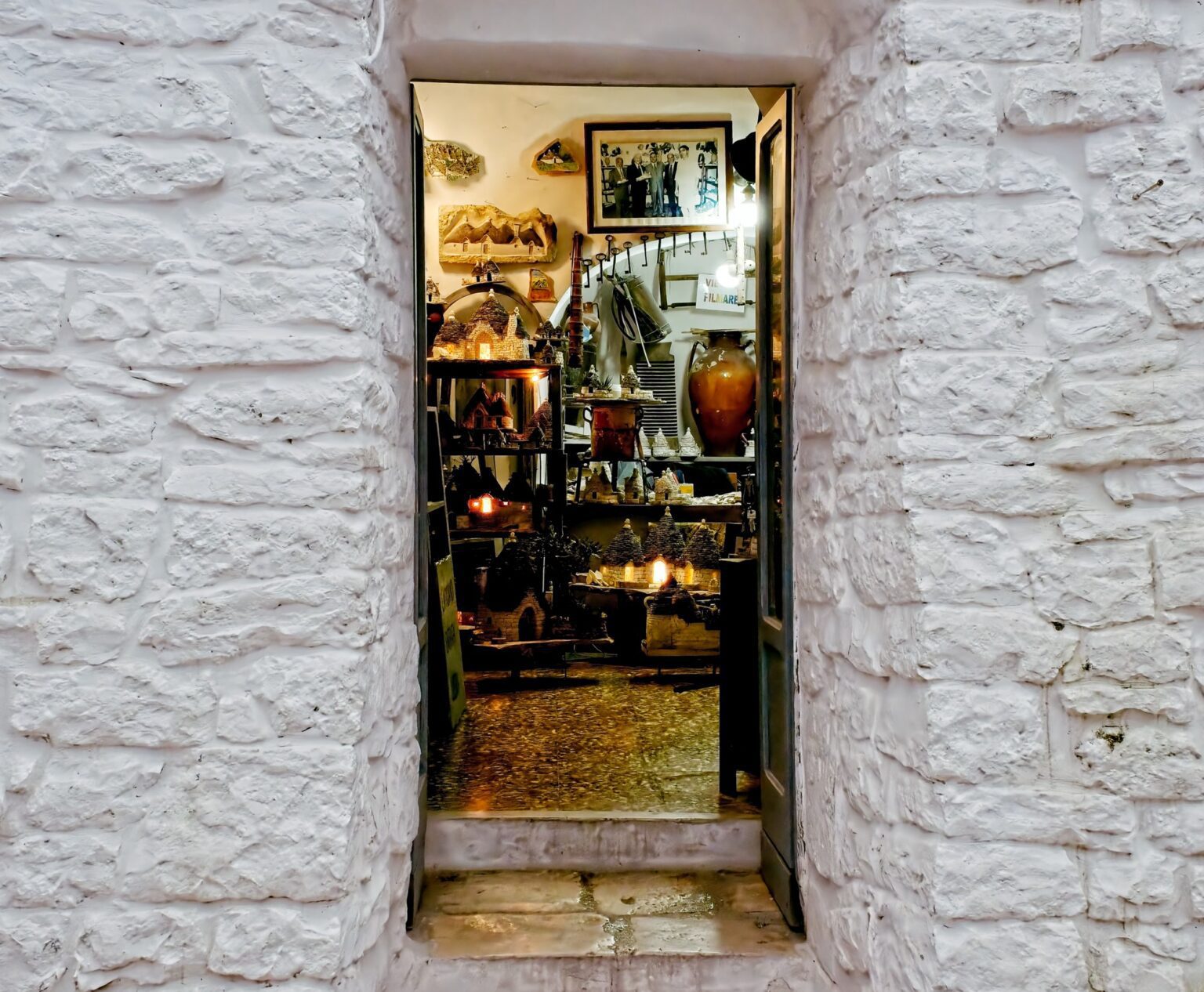 A framed, observational view into a glowing traditional artisan shop through a narrow stone doorway