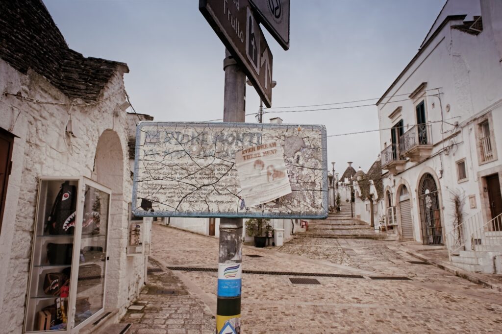 Candid street scene featuring an old information board in the center of the tourist district