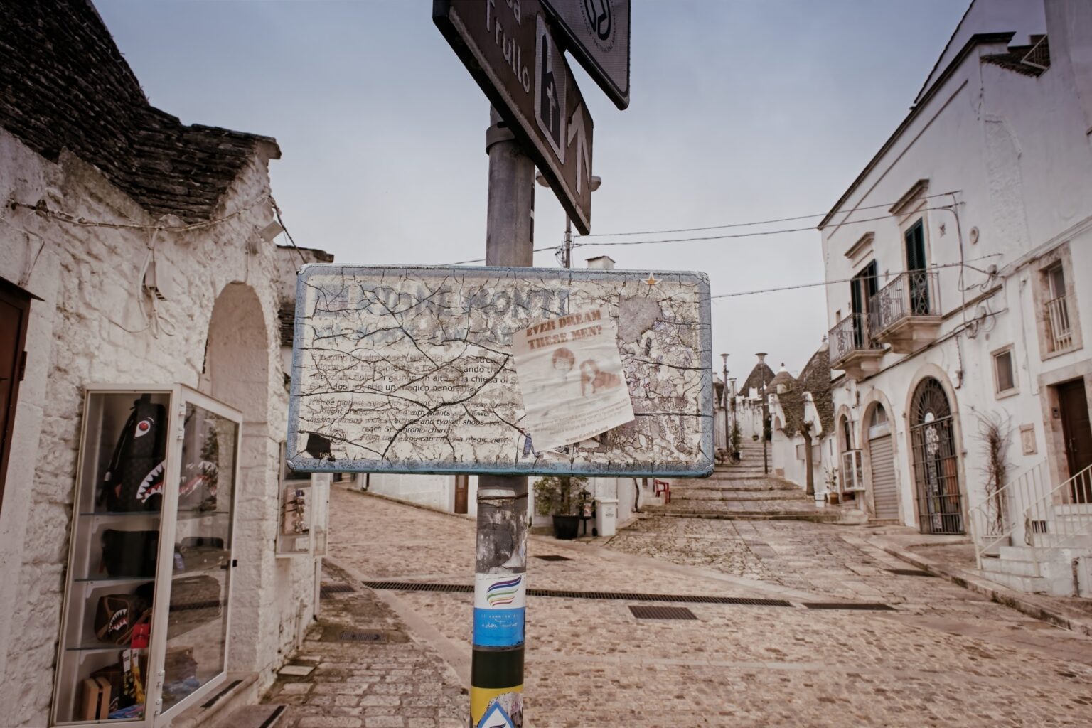 Candid street scene featuring an old information board in the center of the tourist district