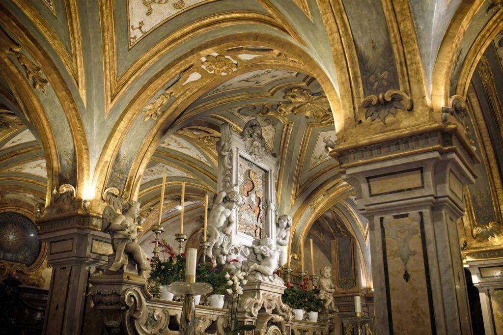 Grand architectural editorial of a Baroque church interior in Bari, featuring ornate gilded arches, marble cherub sculptures, and a central religious icon under dramatic lighting