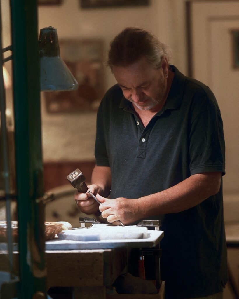 Candid editorial shot of a local craftsman focused on his work inside a dimly lit traditional studio