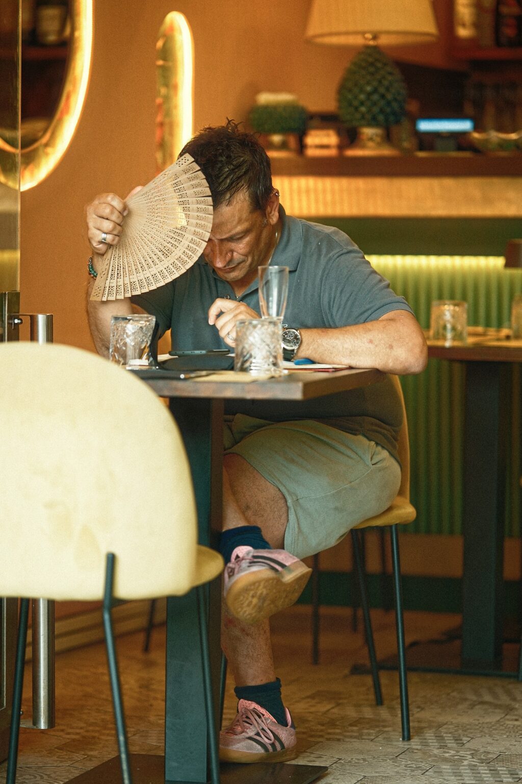Candid editorial moment of a man eating alone at a wooden table in a sun-drenched Taormina restaurant.