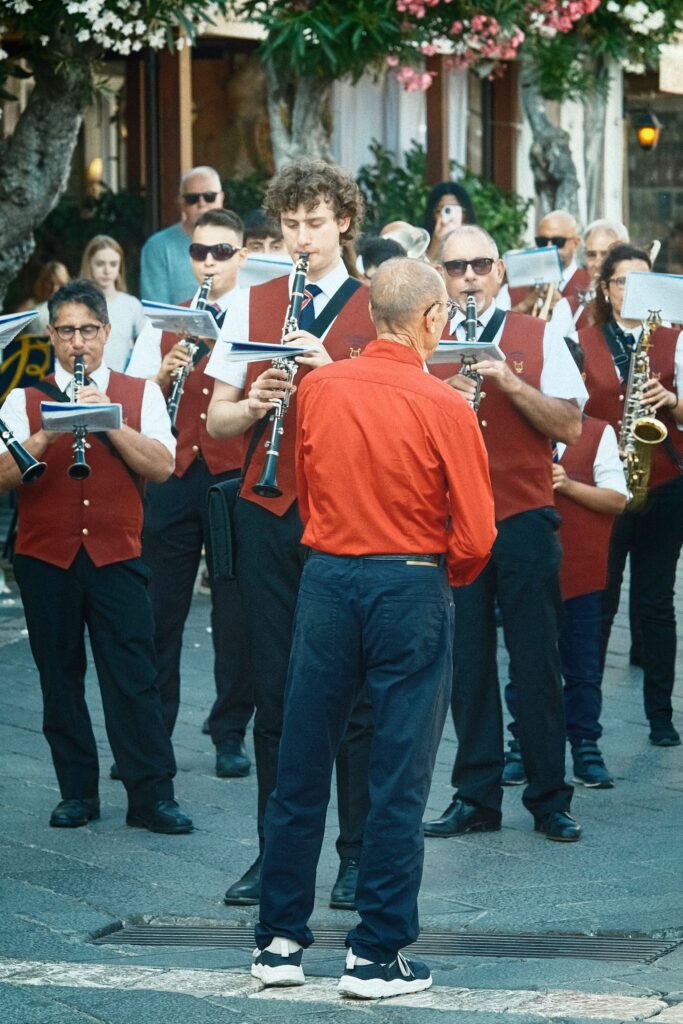 Dynamic documentary photography of a traditional Sicilian brass band performing in the streets of Taormina.