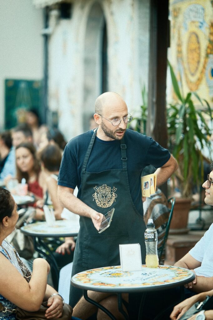 Editorial portrait of a man in an apron working at the Bam Bar restaurant terrace in Sicily
