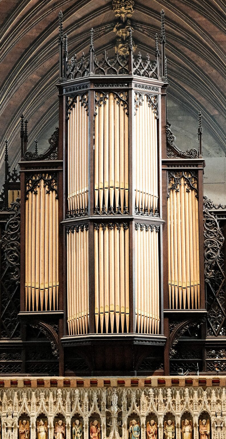 Editorial architectural shot of a grand golden pipe organ, focusing on the vertical rhythm of the pipes