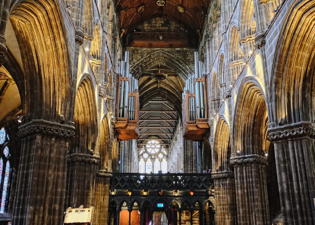 Cinematic documentary photography of the grand Glasgow cathedral interior, featuring intricate wooden ceilings and glowing warm light.
