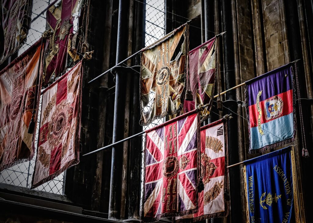 Documentary photography of historic military flags hanging in a dark, high-ceilinged cathedral.