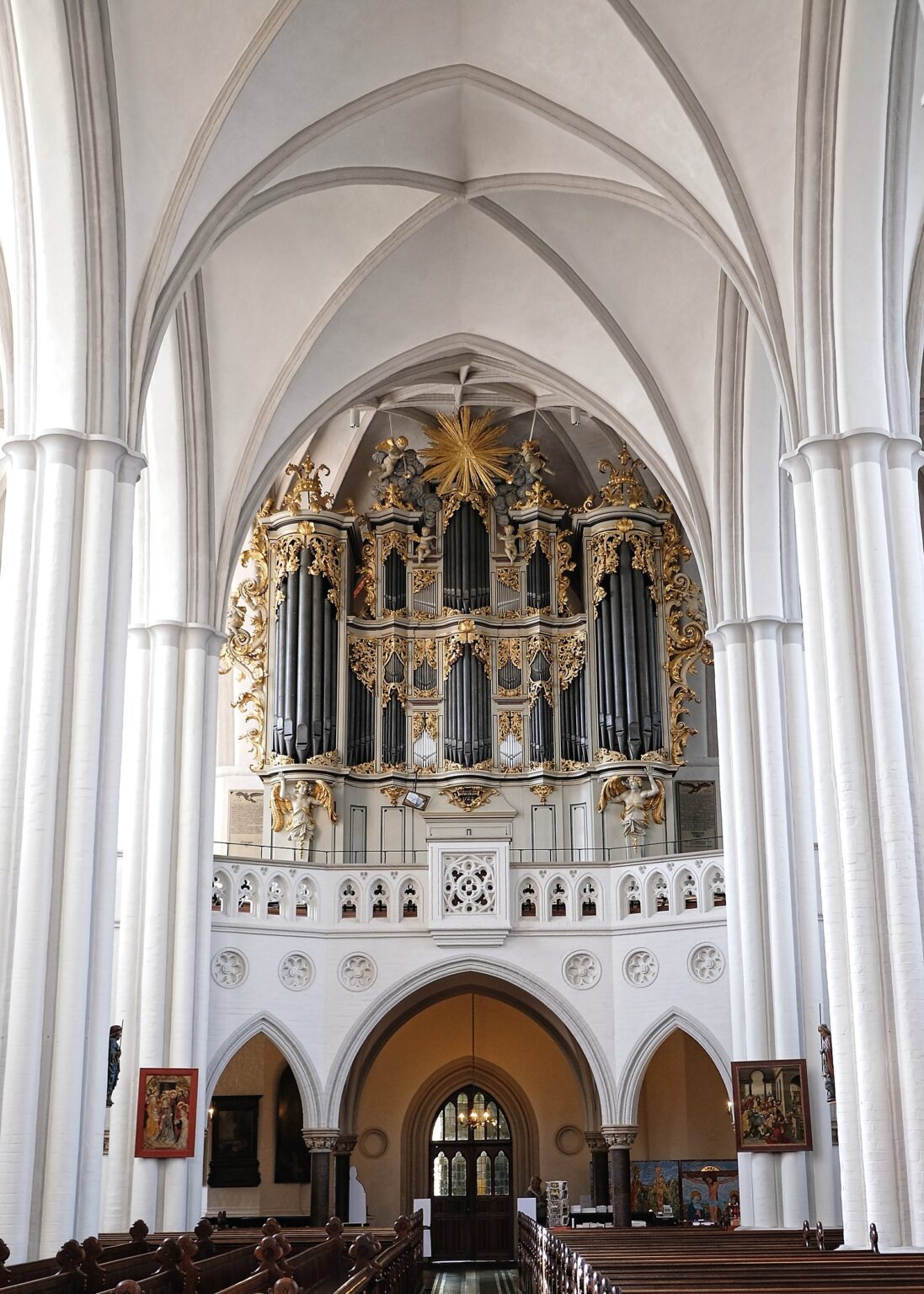 Symmetrical architectural shot of a grand Bavarian white pipe organ set against clean, minimalist church arches