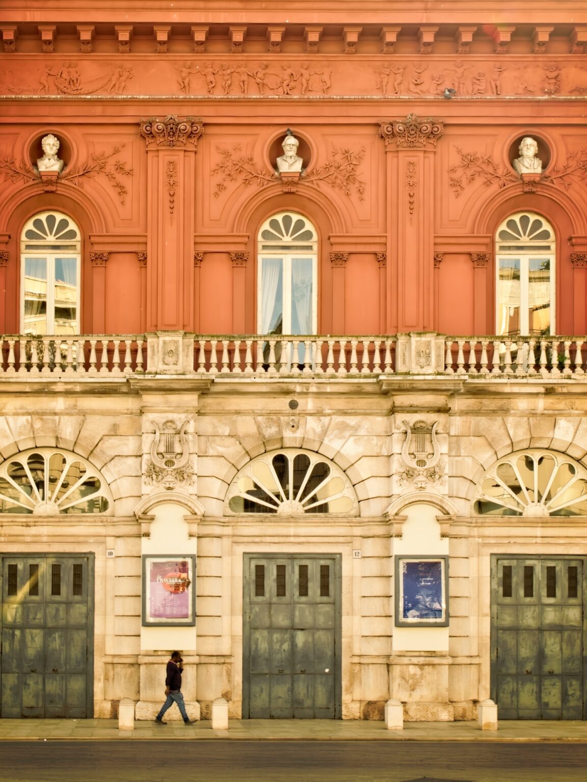 Detailed architectural editorial of a grand red ochre building in Bari, Italy, showcasing ornate Italian craftsmanship