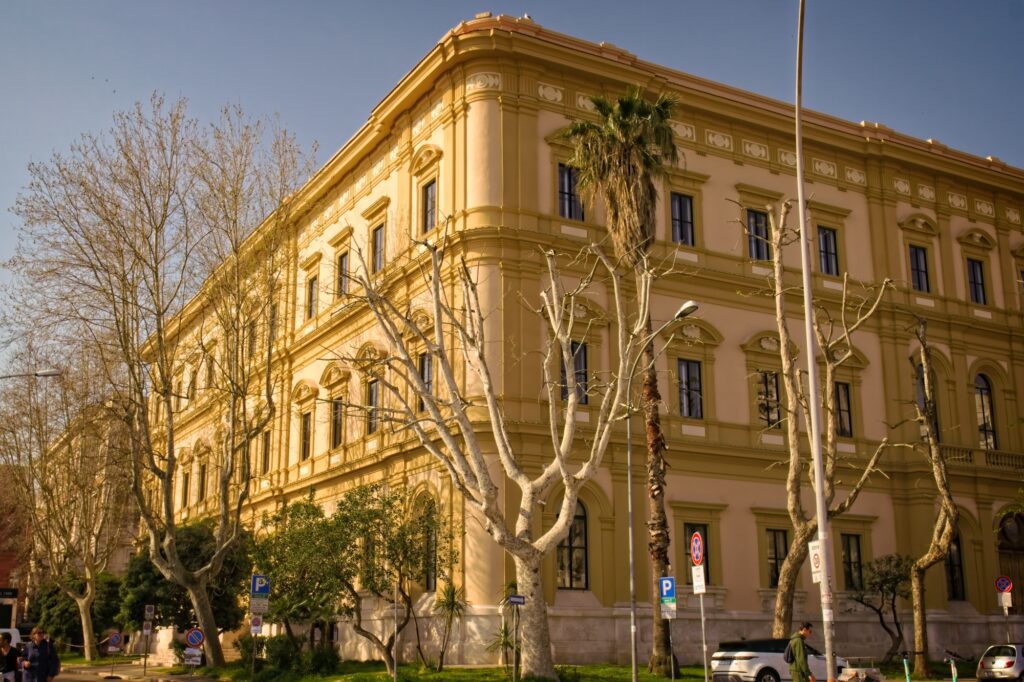 Wide-angle architectural shot of a grand yellow building in Bari's port area, showcasing the city's 'Golden City' aesthetic