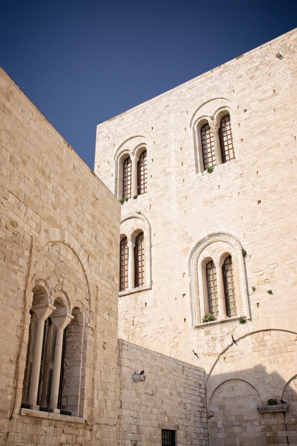Low-angle observational shot of a towering limestone religious building reaching into a clear blue sky