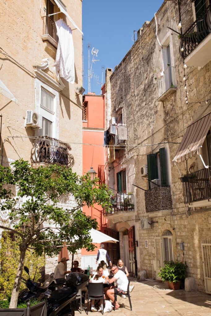 Candid documentary scene of a quiet cafe corner in the sun-drenched streets of Bari