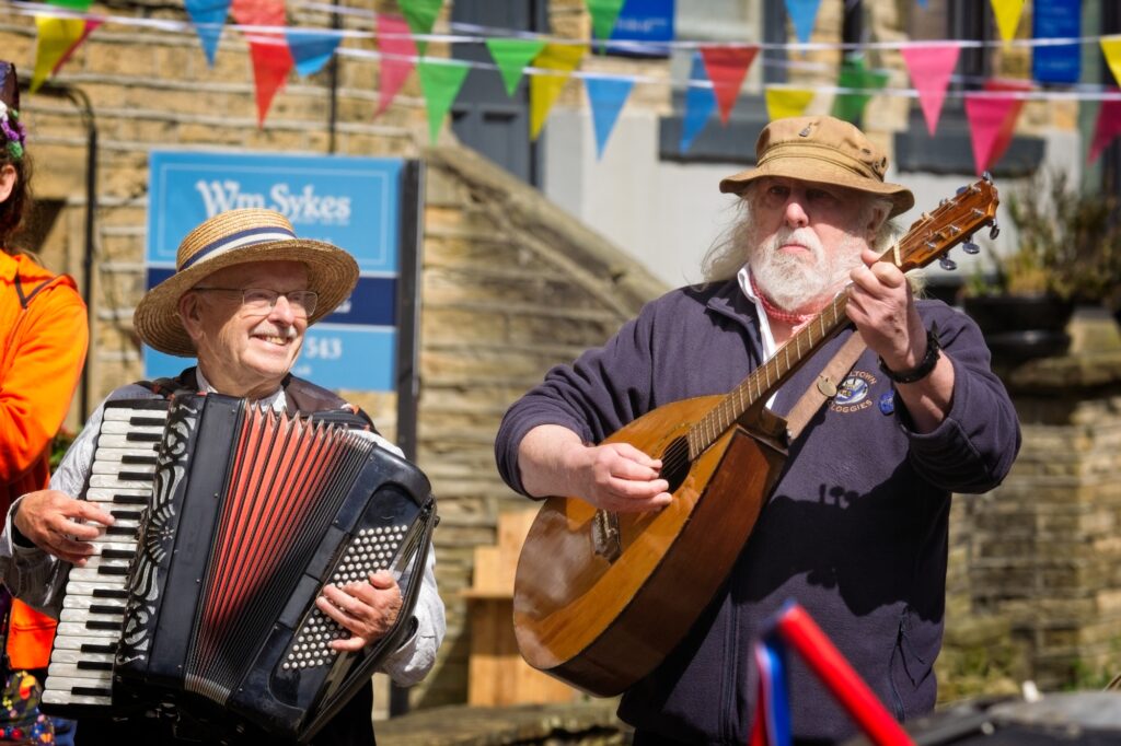 Candid editorial moment of musicians laughing in the streets of Holmfirth, Yorkshire.