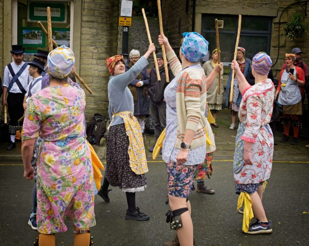 Dynamic documentary photography of the Nora Batty inspired dance group performing in the streets at Holmfirth Festival of Folk, Yorkshire