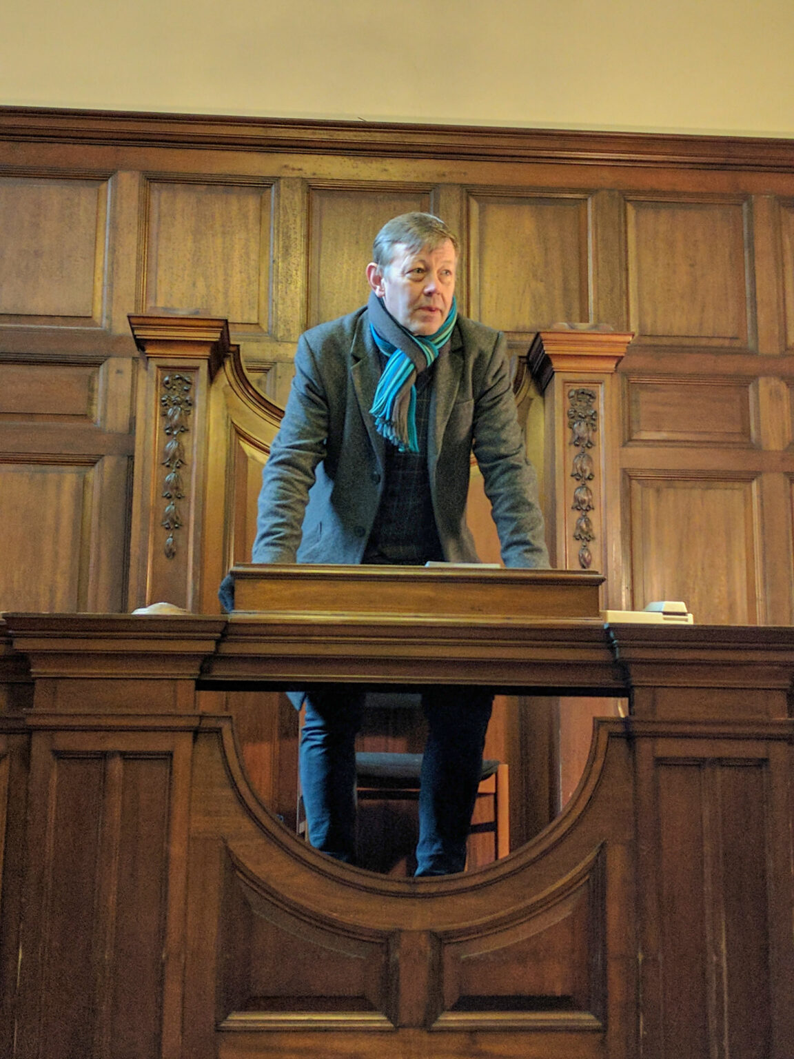 A tour guide describes the activities of a historic court from the Judge's chair.