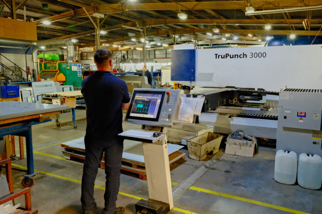 An automated industrial CNC laser cutting machine setup on a spacious factory manufacturing floor.