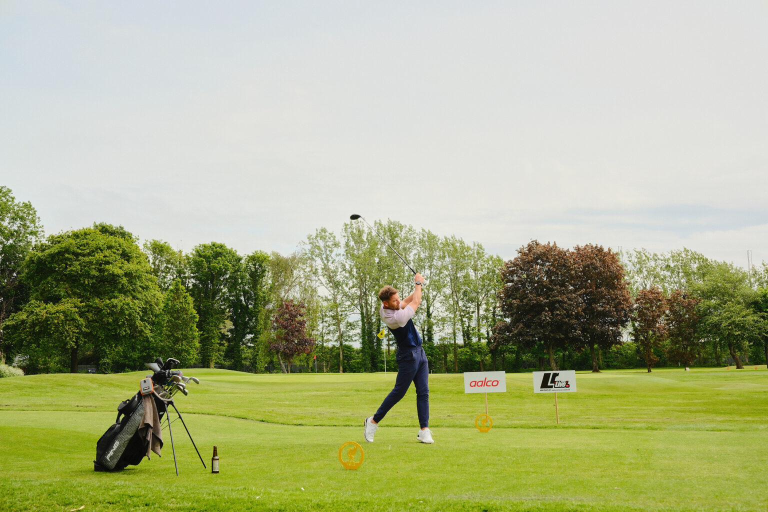 Editorial coverage of a corporate golf player executing a drive down a long fairway.