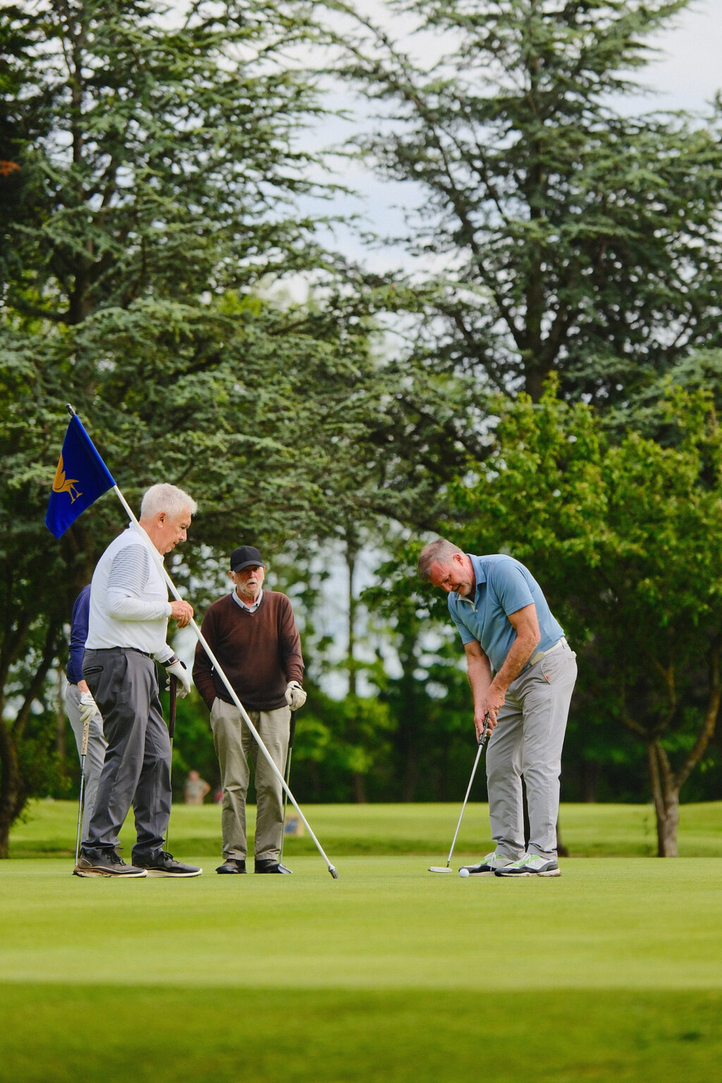 A small group of amateurs tracking a golf ball on a putting green during a corporate network event.
