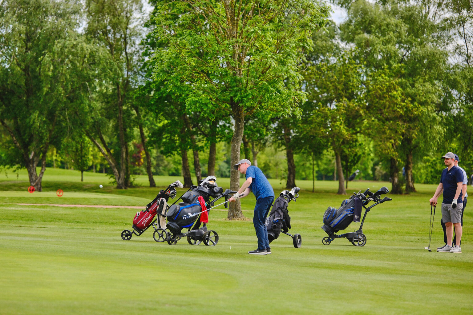 Observational documentary photography of attendees with pull carts playing an outdoor corporate golf match.