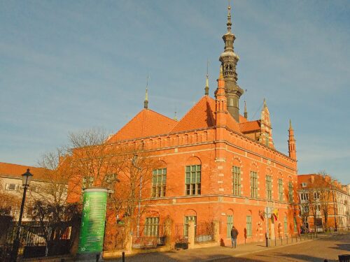 Wide view of the historic red-brick Old Town Hall featuring its slender clock tower and Renaissance architectural details.